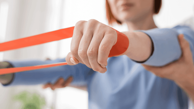 Kvinna som har tränar med gummiband runt båda handlederna.