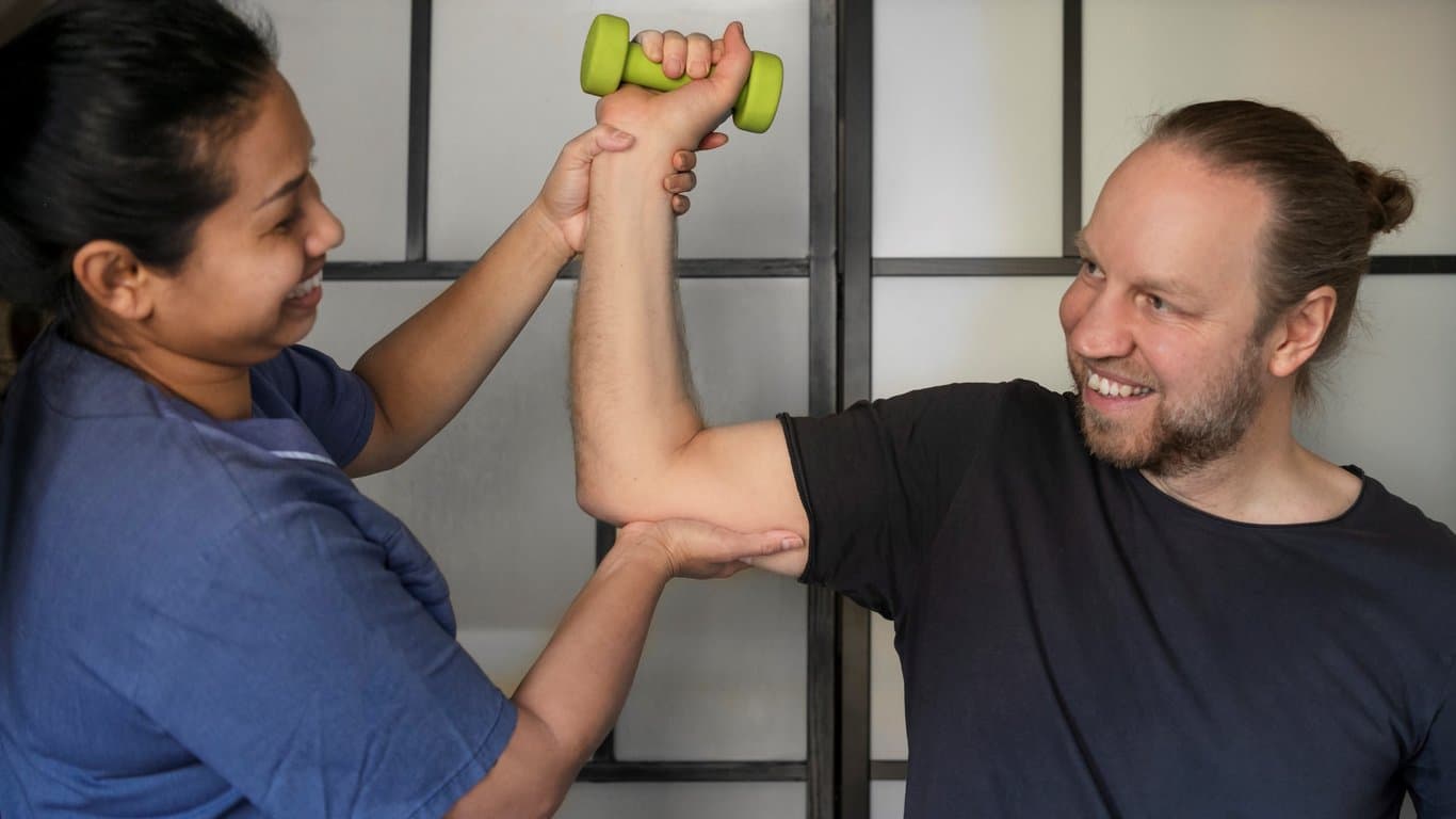 Man hos sjukgymnast som håller upp armen  och håller i en tyngd