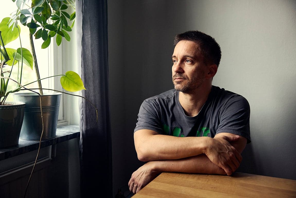 Bild på Mikael Hillgren sittandes vid köksbord och kollar ut genom fönstret.
Foto: Albin Handig